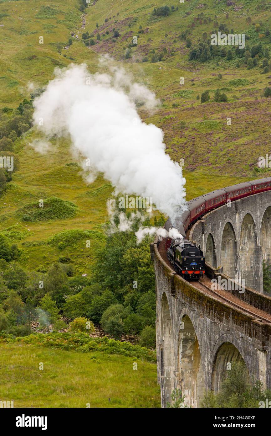 GLENFINNAN, SCOTLAND - SEPTEMBER 3 2021: Crowds of people gather to watch the traditional Jacobite Steam Train crossing the famous viaduct at Glenfinn Stock Photo