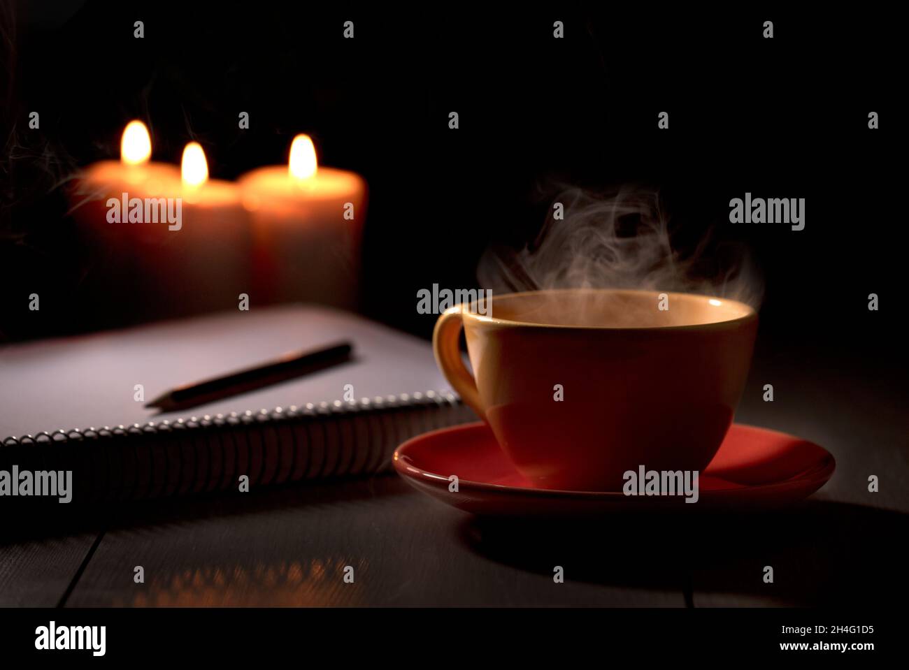 Premium Photo  Cup of tea with hot smoke and three burning candles on the  desk at home power outage