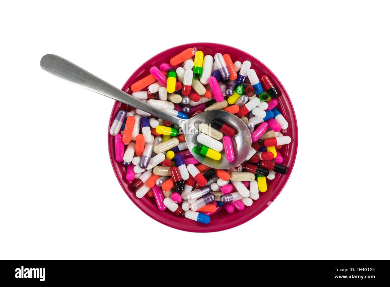 Bowl and spoon filled with colorful pills and capsules. Stock Photo