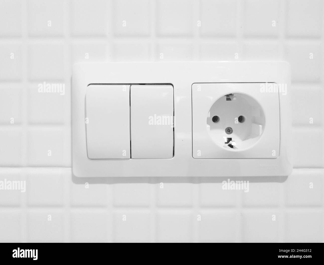 New white switch and socket on a tiled wall - close-up Stock Photo