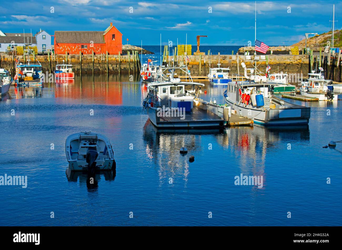 Red fishing shack in Rockport, Massachusetts, Motif # 1, and a nearby harbor filled with nautical vessels -23 Stock Photo