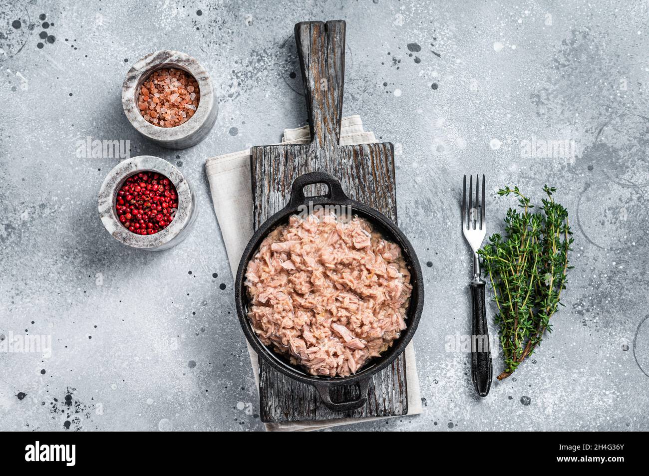 Canned tuna fish with oil in a pan. Gray background. top view Stock