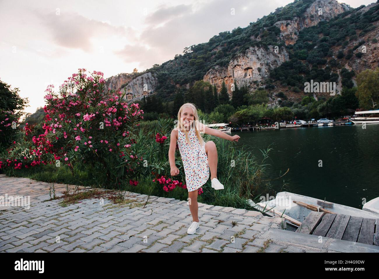 Photo of a pretty funny excited little girl by the river in a white ...