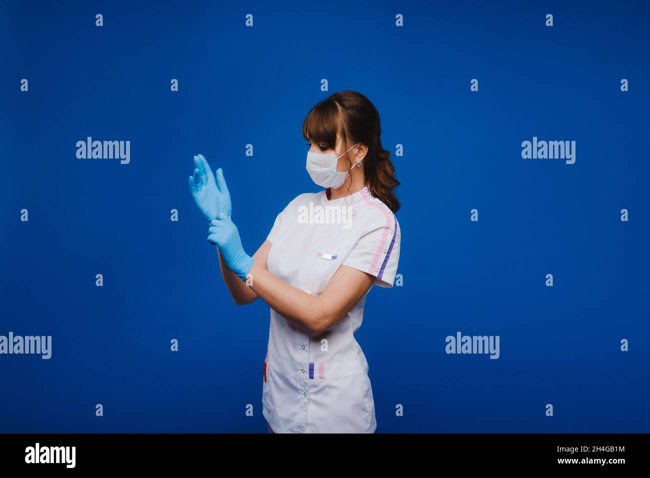 Beautiful female doctor or nurse wearing protective mask and latex or rubber gloves on grey background with copyspace. Health care concept. Stock Photo