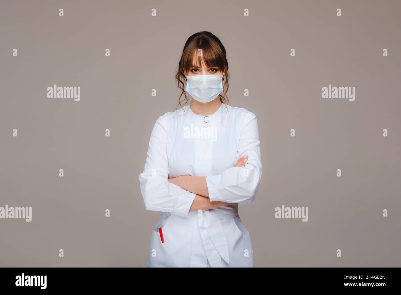 beautiful young girl in a white medical coat, medical mask and arms ...