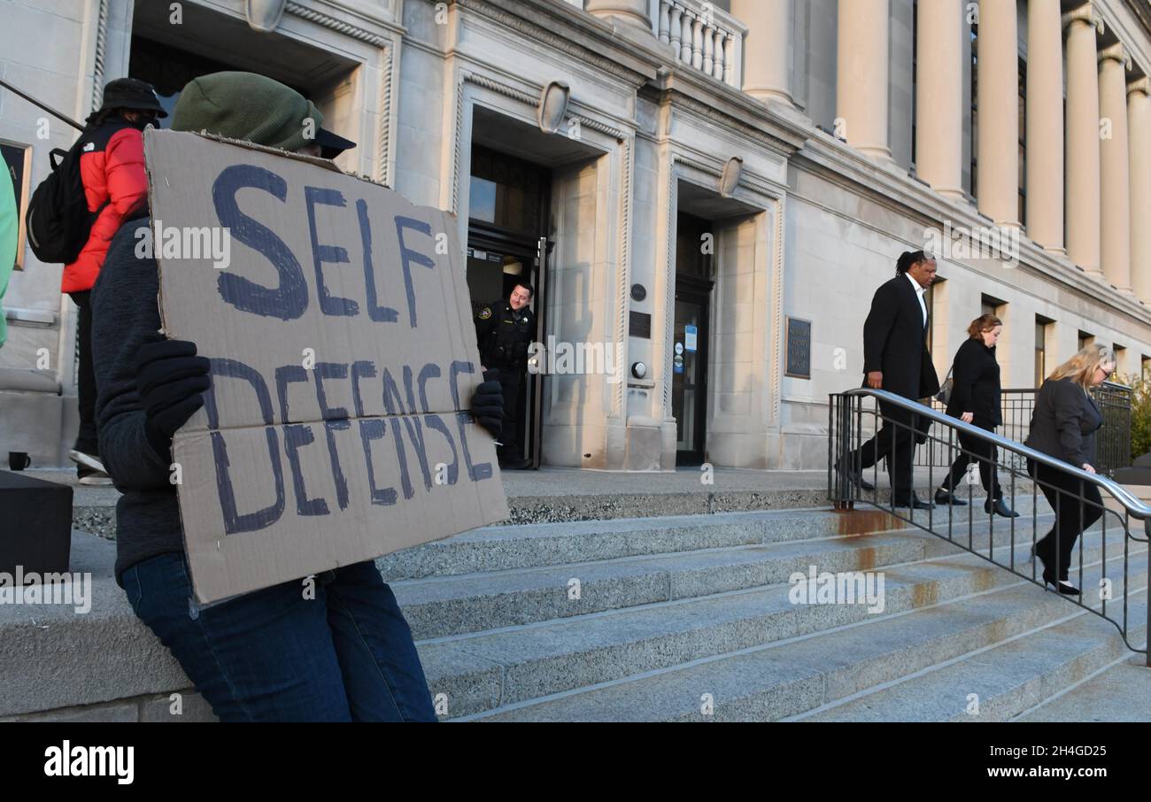 Kenosha, Wisconsin, USA. 2nd Nov, 2021. A supporter of Kyle Rittenhouse, who declined to giver her name, is outside the courthouse while Jacob BlakeÃ¢â‚¬â„¢s uncle, JUSTIN BLAKE walks back and forth behind her with a Pan-African flag at the end of court during the Kyle Rittenhouse trial at the Kenosha County Courthouse Tuesday November 2, 2021. Meanwhile RittenhouseÃ¢â‚¬â„¢s mother WENDY RITTENHOUSE and sister FAITH RITTENHOUSE, right, leave the courthouse. Rittenhouse faces seven charges including one count each of First Degree Intentional Homicide, First Degree Reckless Homicide Stock Photo