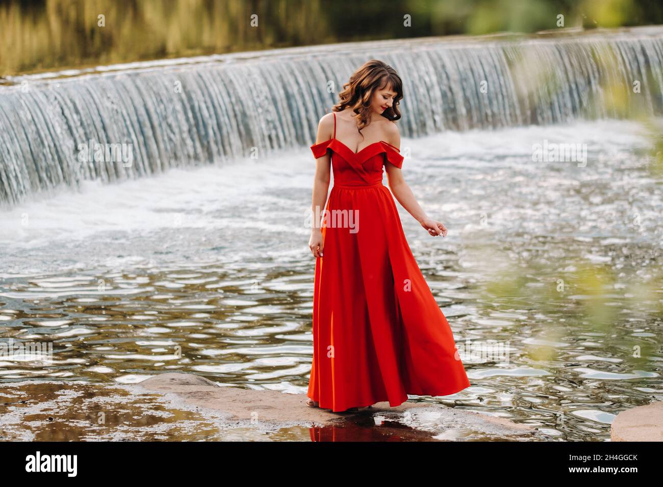 girl in a long red dress near the lake in the Park at sunset Stock ...