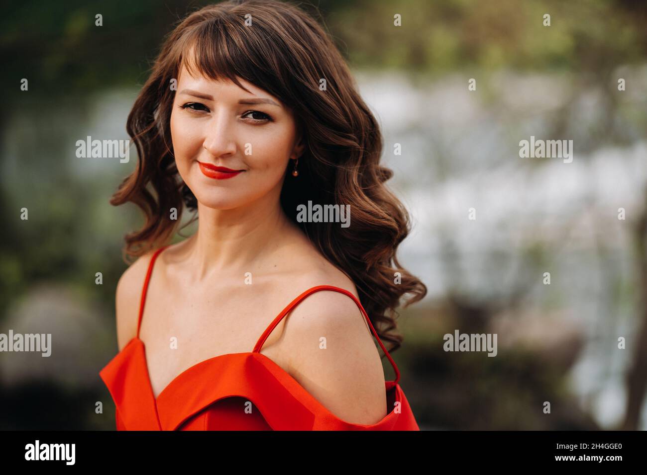 portrait of a young beautiful girl with long brown hair, in a long red ...