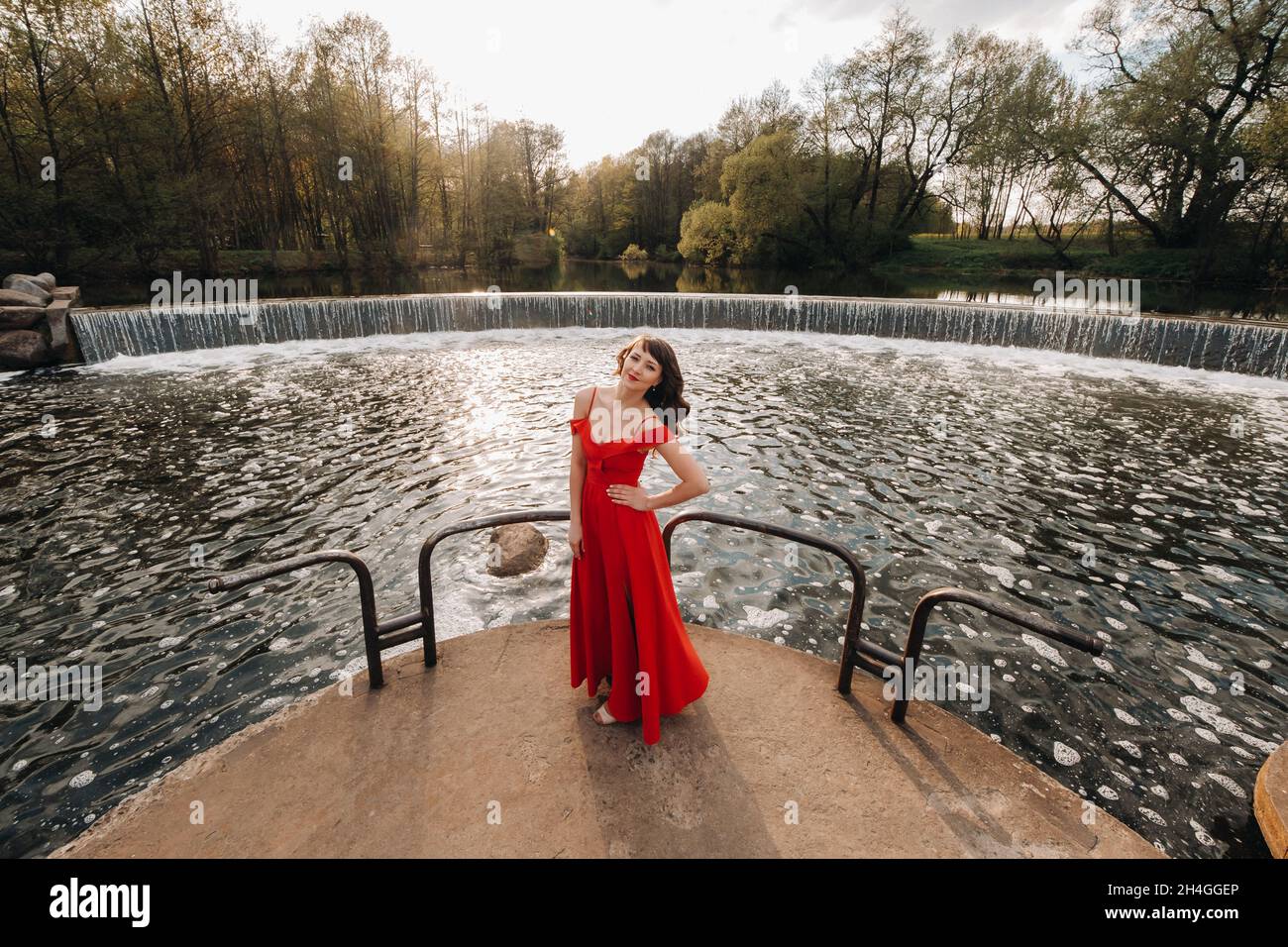 girl in a long red dress near the lake in the Park at sunset Stock ...