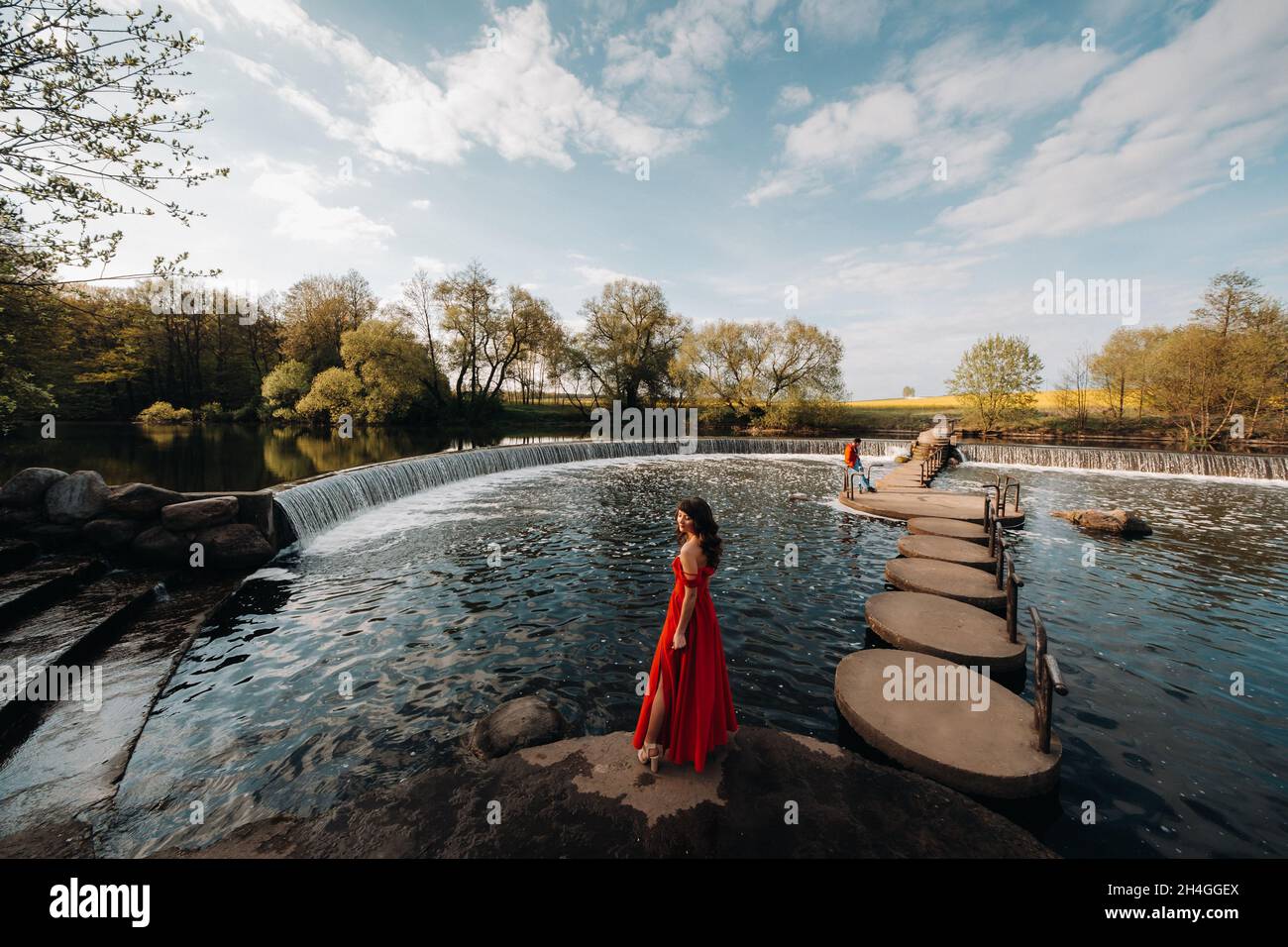 girl in a long red dress near the lake in the Park at sunset Stock ...