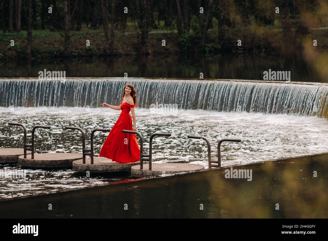 girl in a long red dress near the lake in the Park at sunset Stock ...
