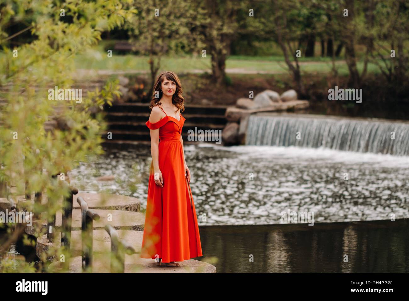 girl in a long red dress near the lake in the Park at sunset Stock ...