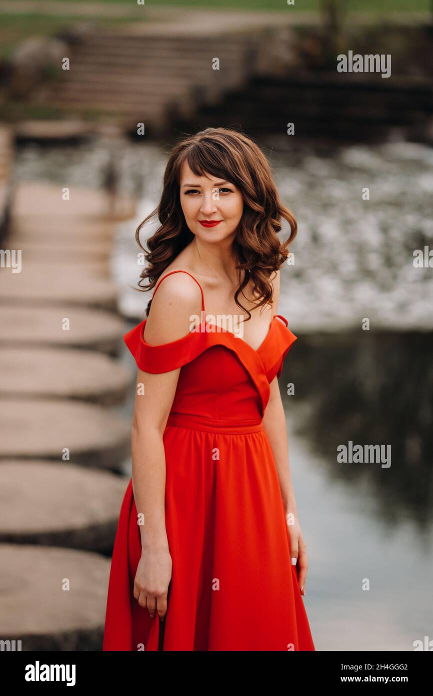 girl in a long red dress near the lake in the Park at sunset Stock ...