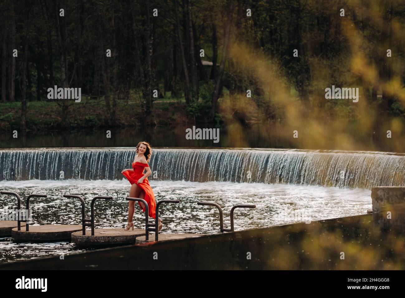 girl in a long red dress near the lake in the Park at sunset Stock ...