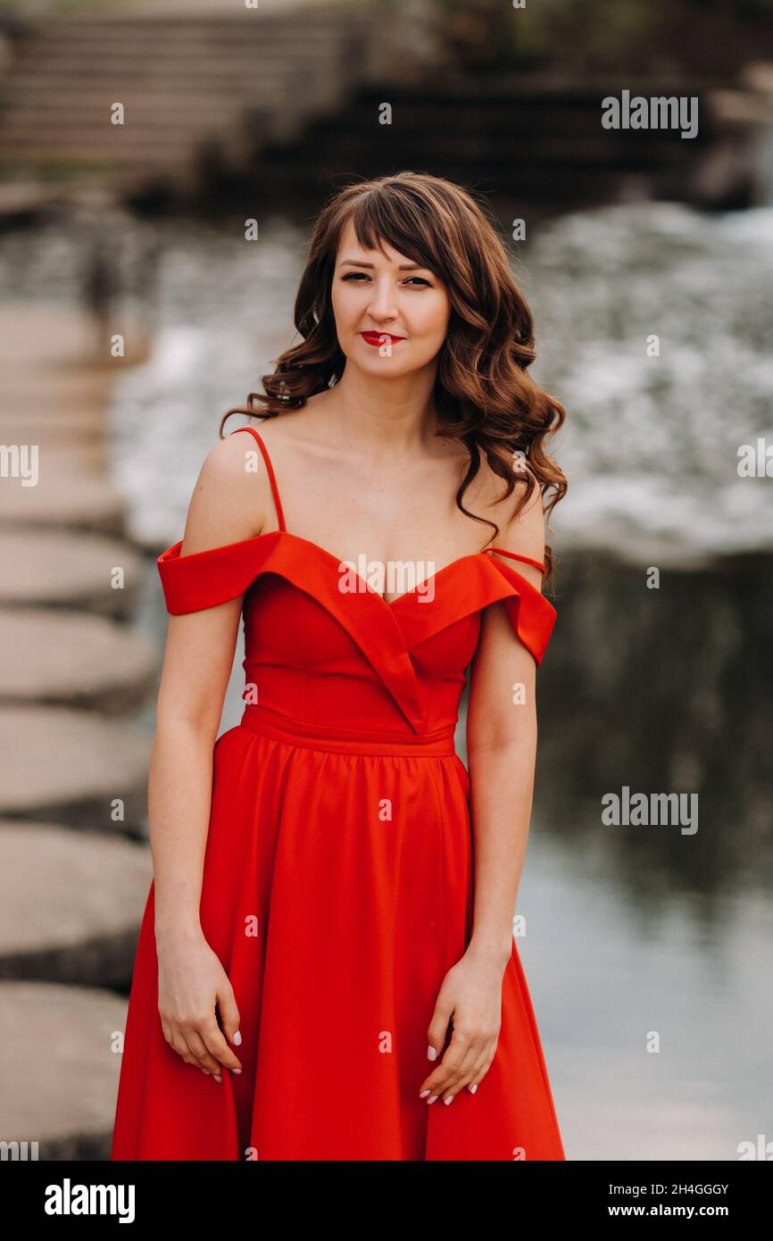 girl in a long red dress near the lake in the Park at sunset Stock ...