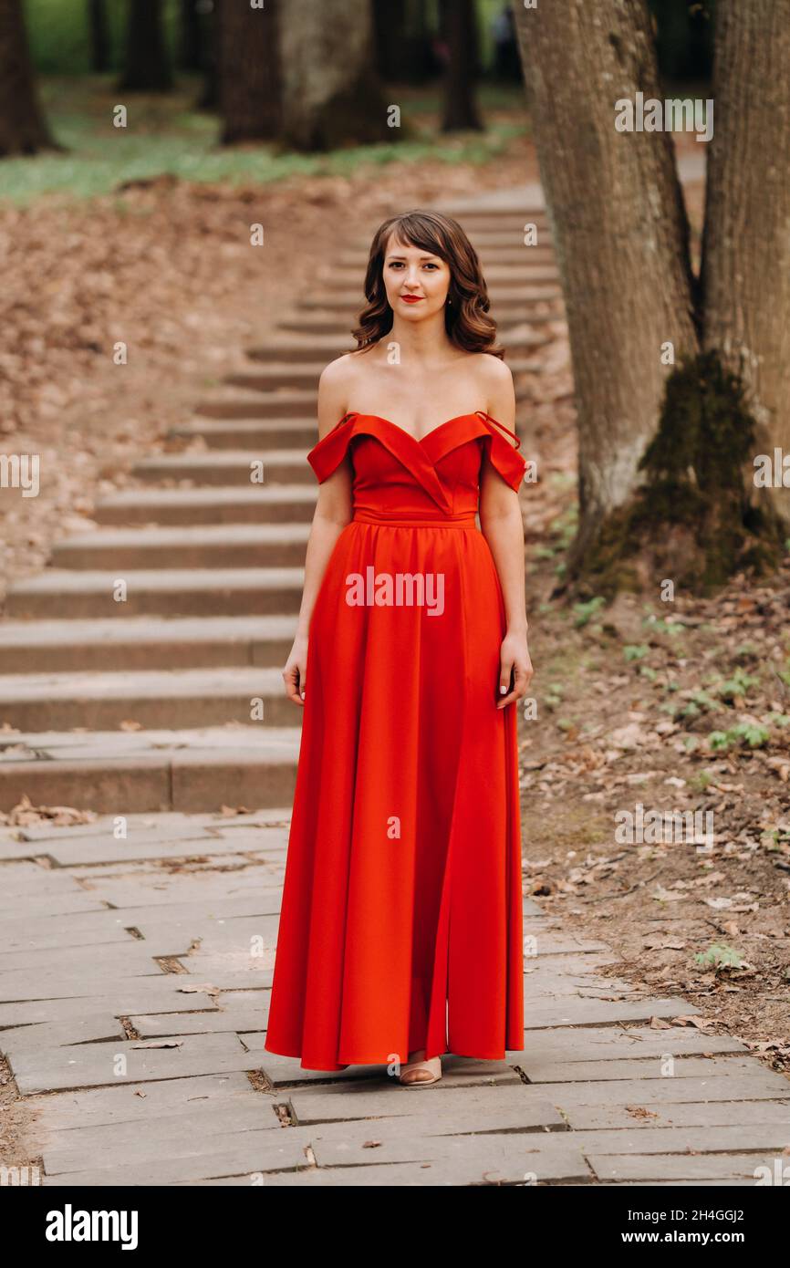 Spring Portrait of a laughing girl in a long red dress with long hair ...