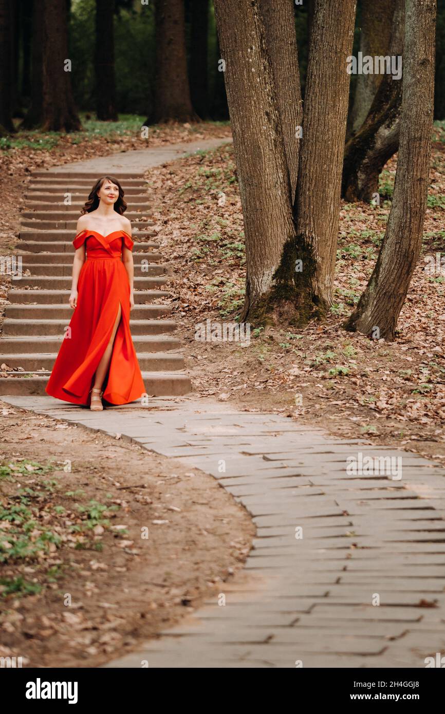 Spring Portrait of a laughing girl in a long red dress with long hair ...