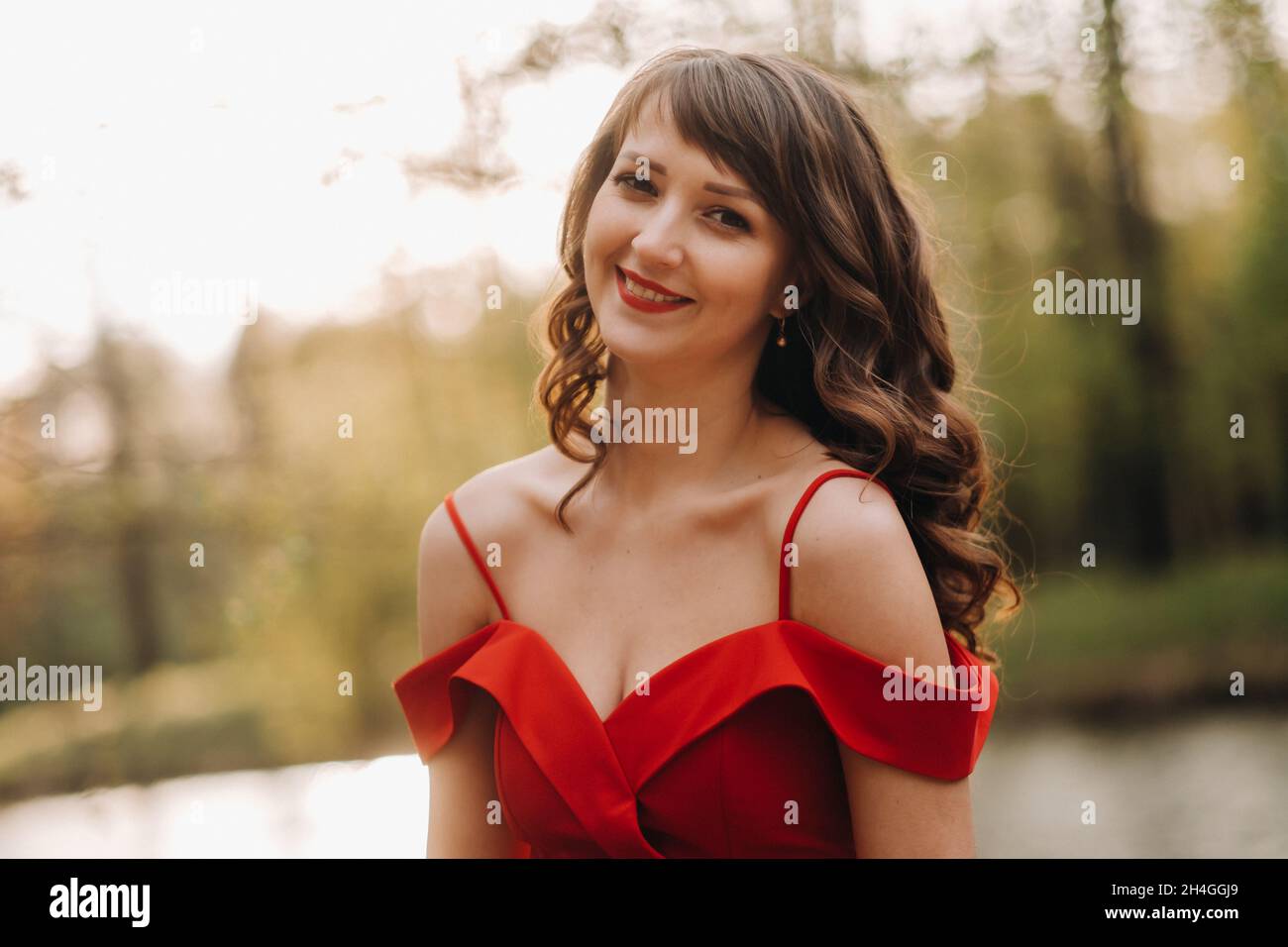 Spring Portrait of a laughing girl in a long red dress with long hair ...