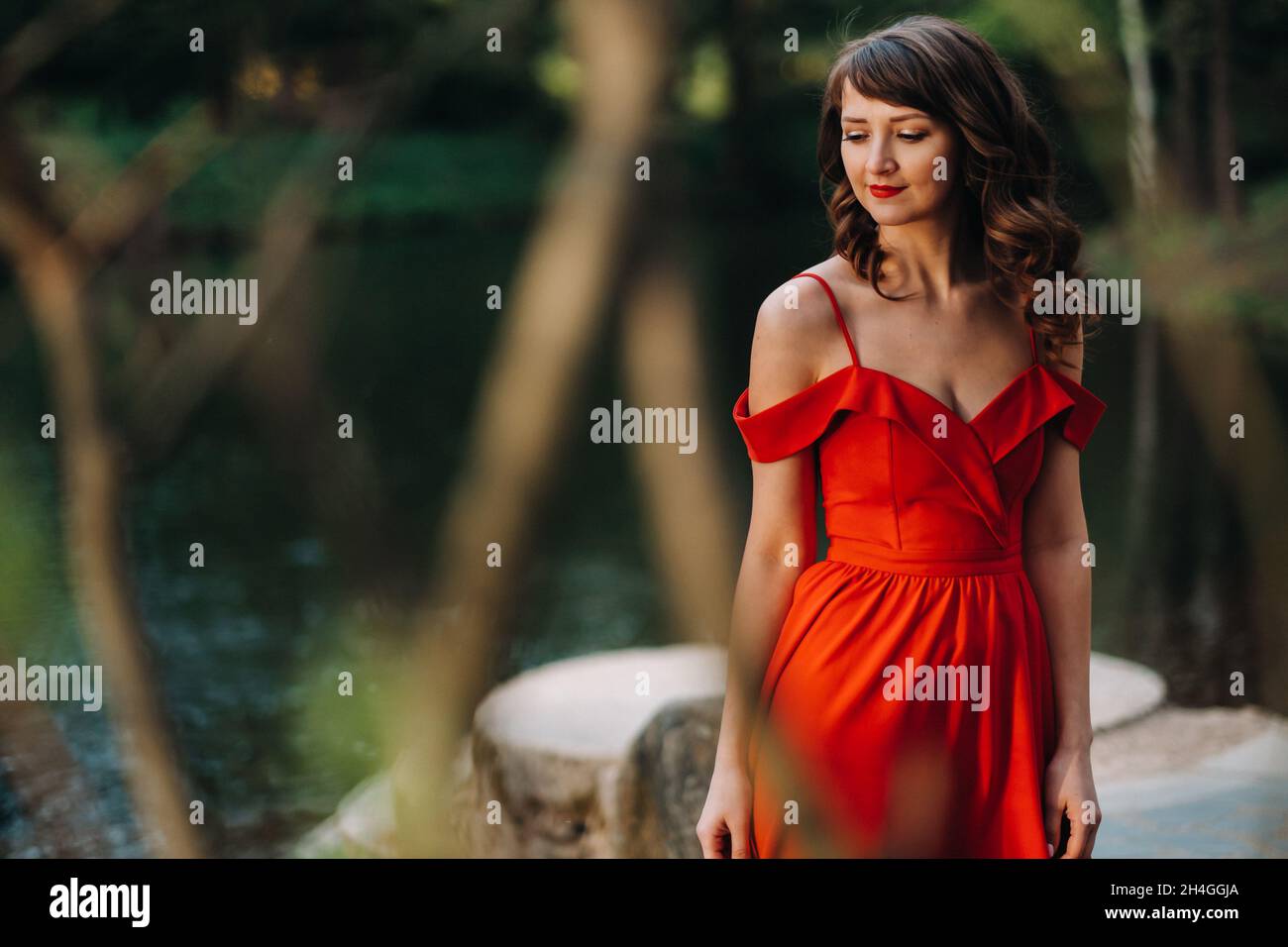 Spring Portrait of a laughing girl in a long red dress with long hair ...