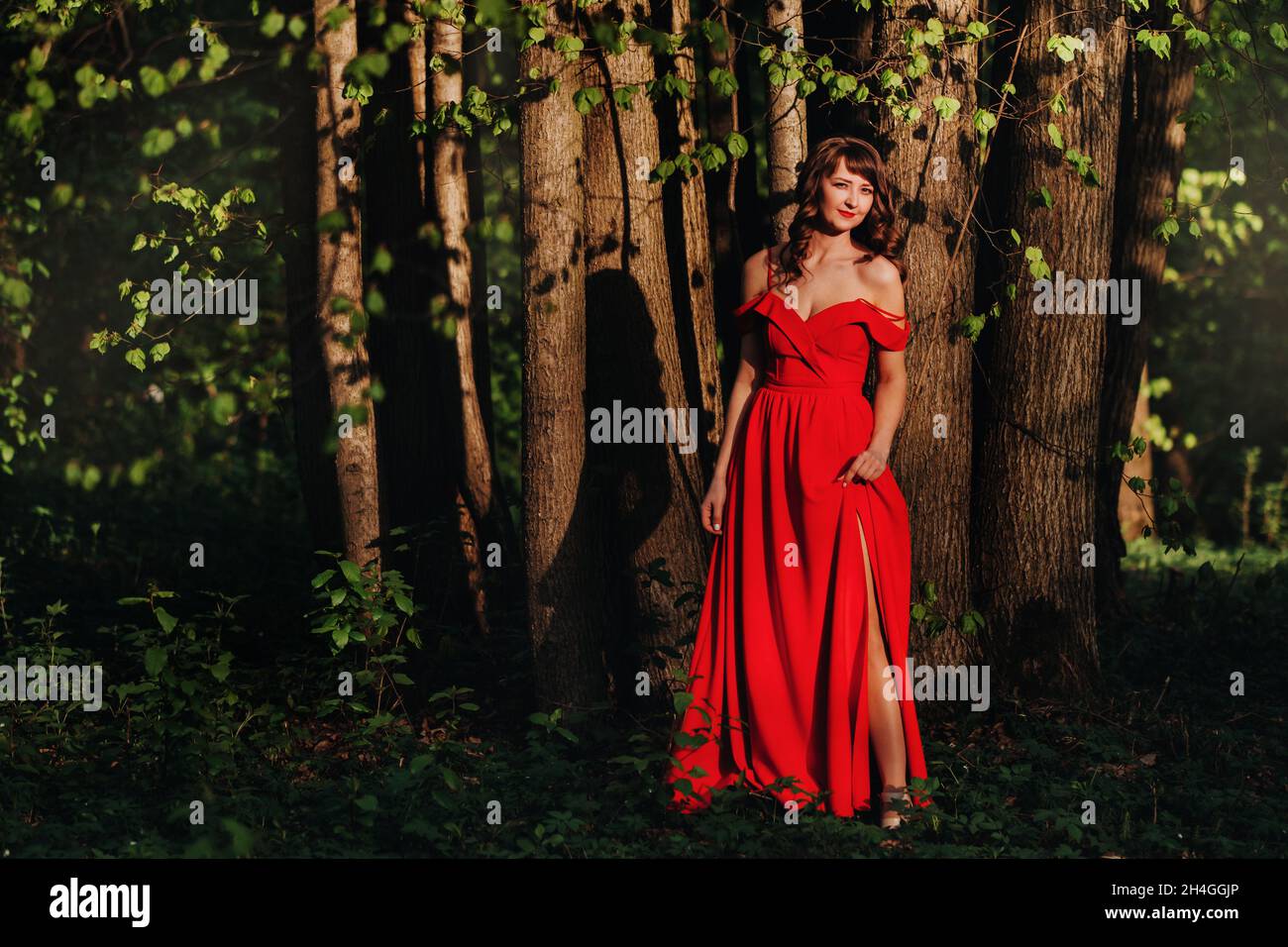 Spring Portrait of a laughing girl in a long red dress with long hair ...