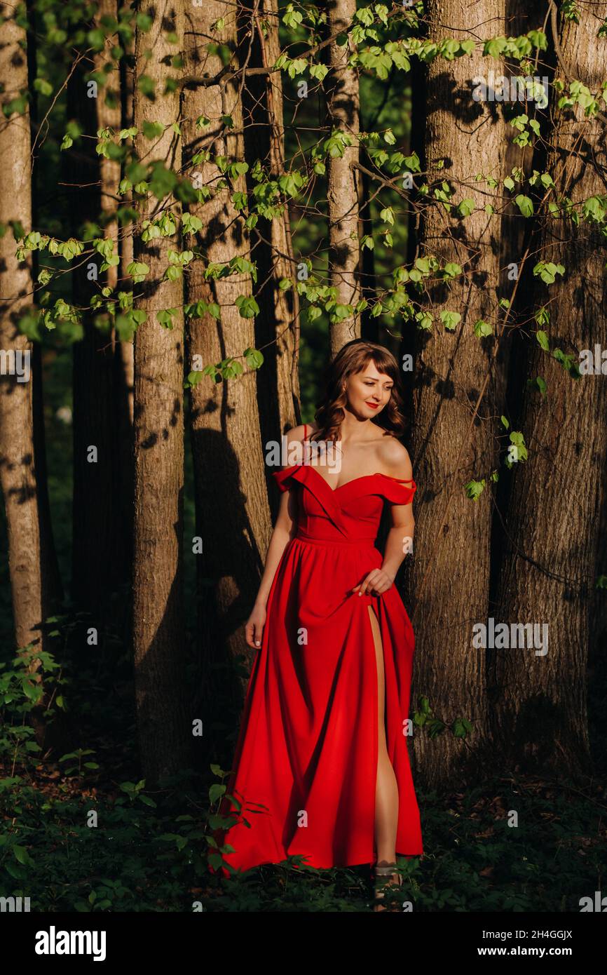 Spring Portrait of a laughing girl in a long red dress with long hair ...