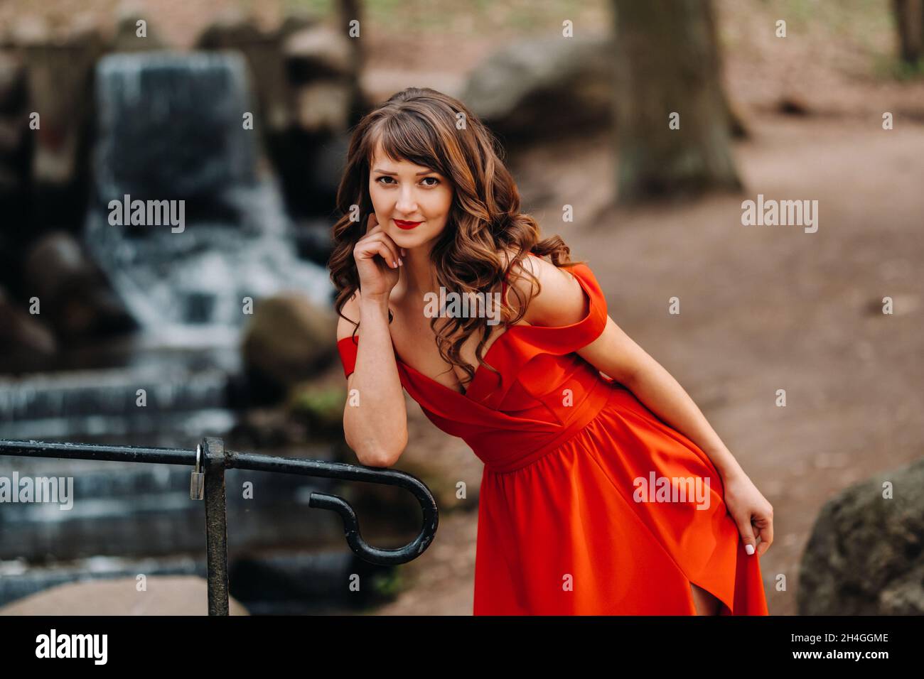 Spring Portrait of a laughing girl in a long red dress with long hair ...