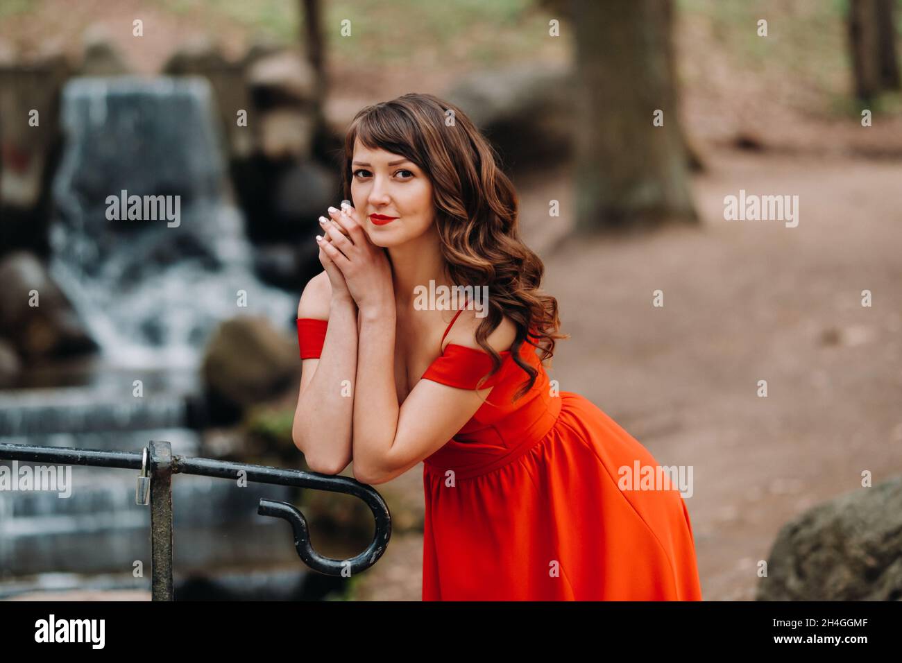 Spring Portrait of a laughing girl in a long red dress with long hair ...