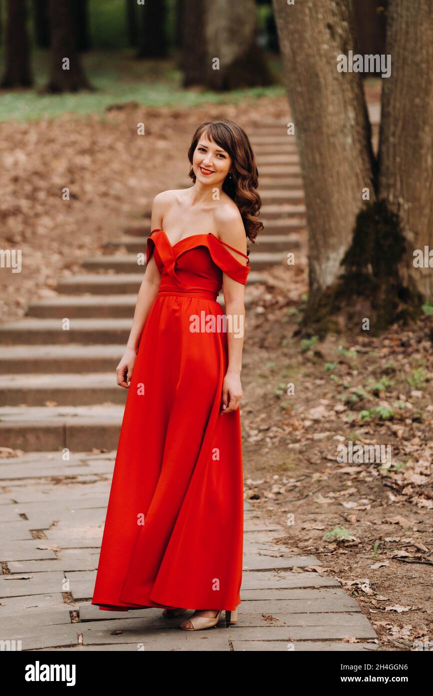 Spring Portrait of a laughing girl in a long red dress with long hair ...