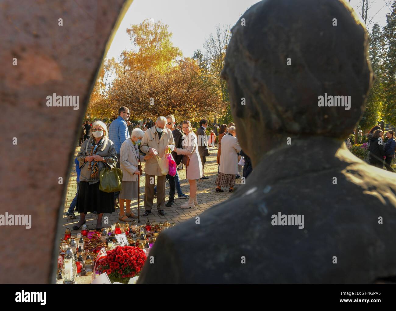 Krakow, Poland. 01st Nov, 2021. People seen at Meritorious Avenue at the Rakowice Cemetery with candles lit in front of the singer Marek Grechuta's grave, during All Saints Day, a traditional feast at Krakow Catholic cemeteries. (All Day of the Dead) Credit: SOPA Images Limited/Alamy Live News Stock Photo