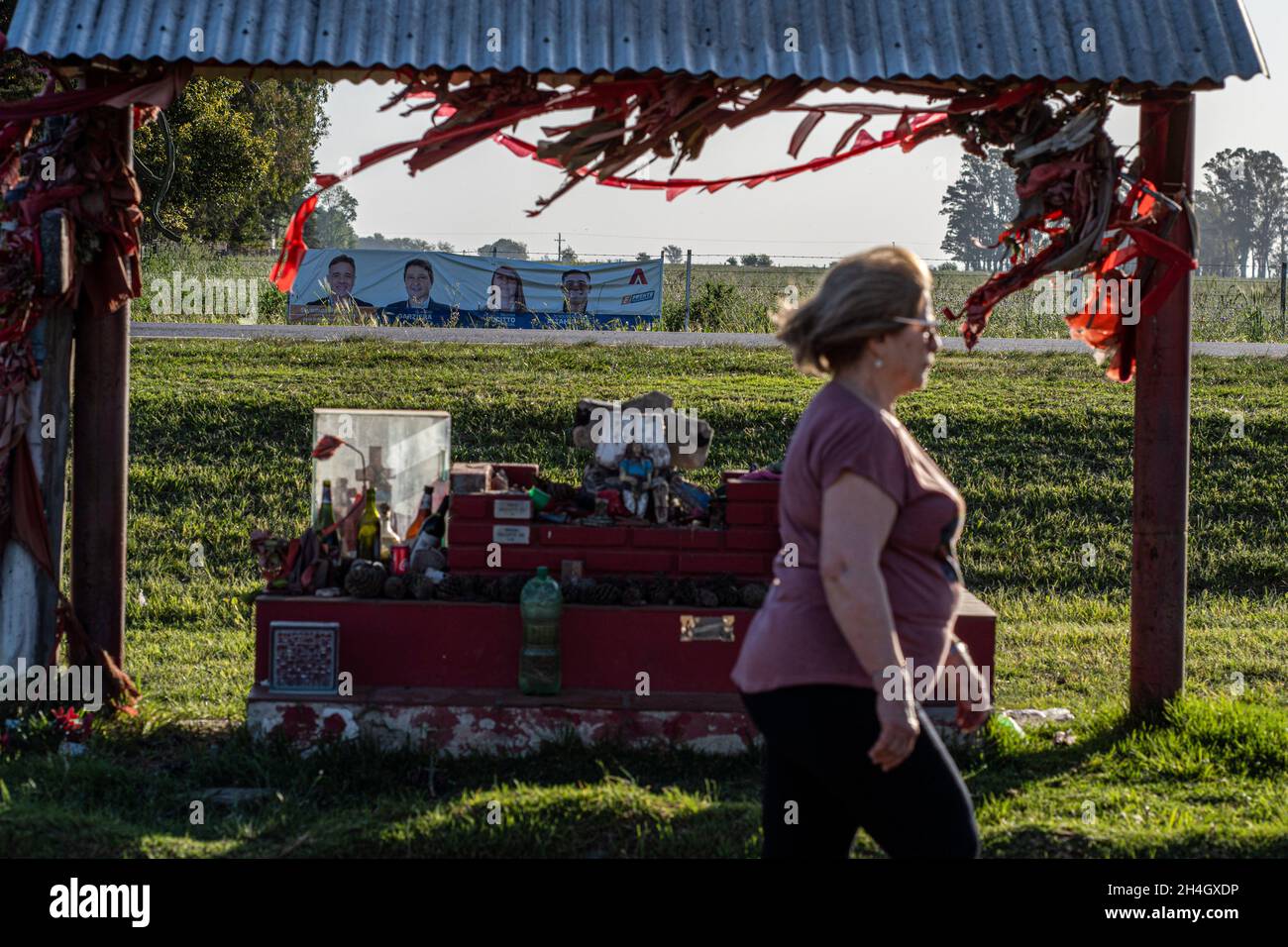 Firmat, Argentina. 21st Oct, 2021. A woman walks past Gauchito Gil shrine, with election poster in the background.On Nov 14, the country will hold a mid term election, renewing one third of the Senate's seats and a half in the Chamber of Deputies. (Photo by Patricio Murphy/SOPA Images/Sipa USA) Credit: Sipa USA/Alamy Live News Stock Photo