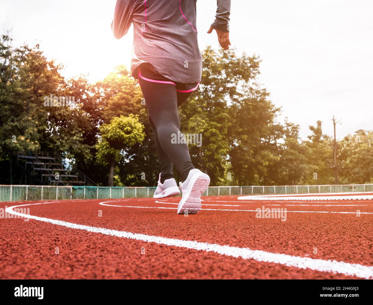 Athletic woman in sport clothes running on stadium track. Female runner