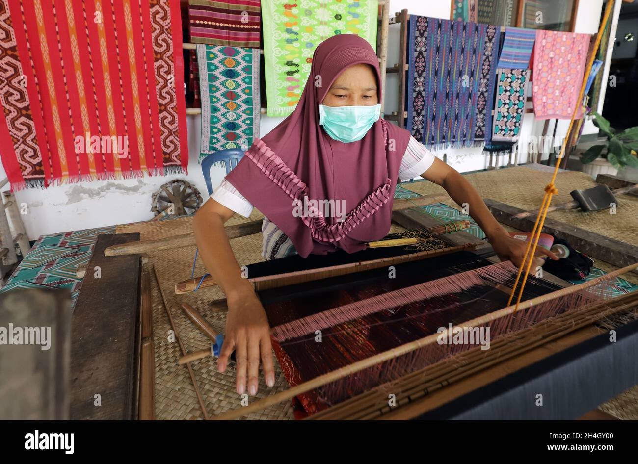 Lombok, West Nusa Tenggara, Indonesia-Oct 25, 2021: A woman is weaving using a traditional loom Stock Photo