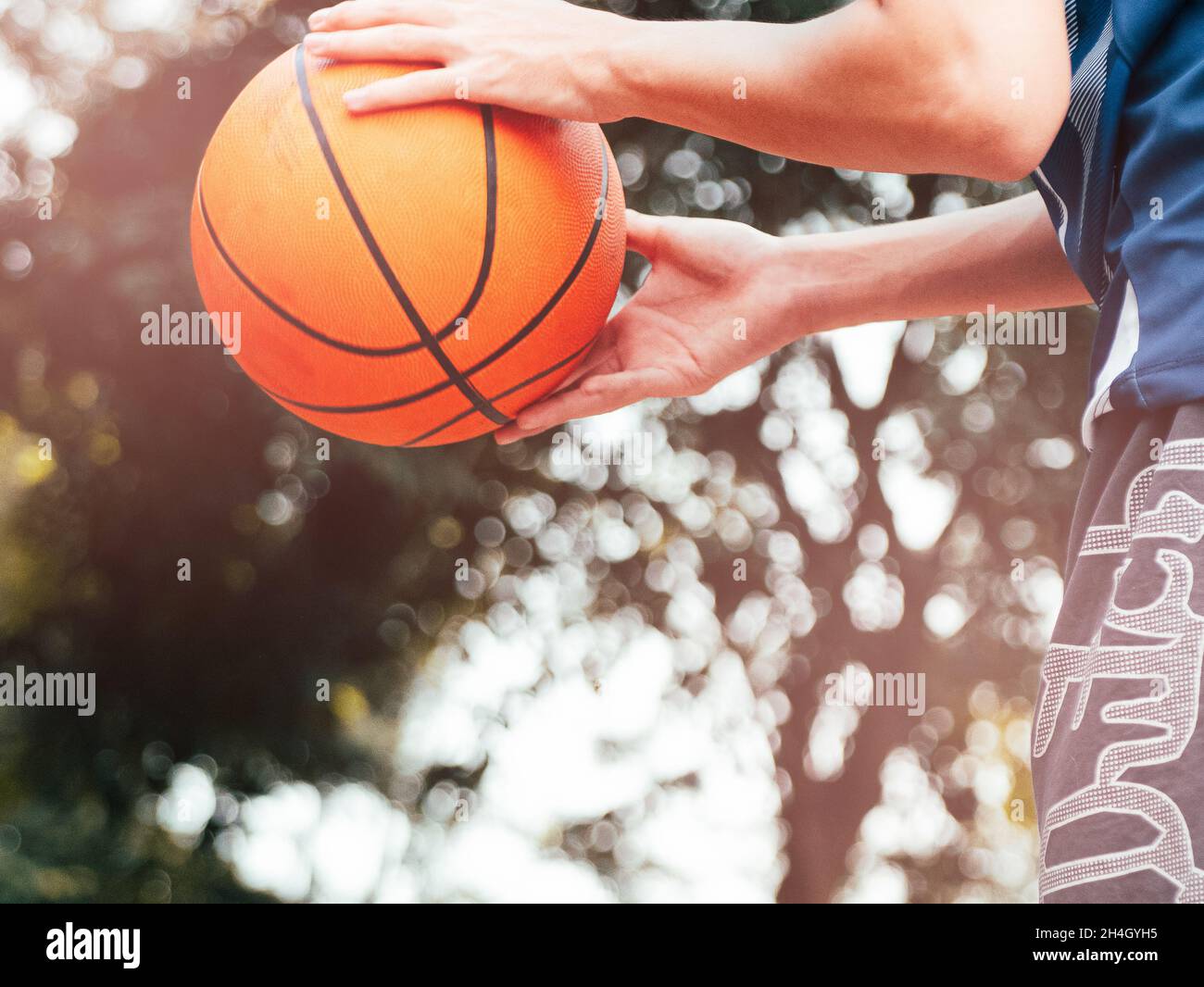 A teenage boy holding a basketball prepares to throw the ball into the