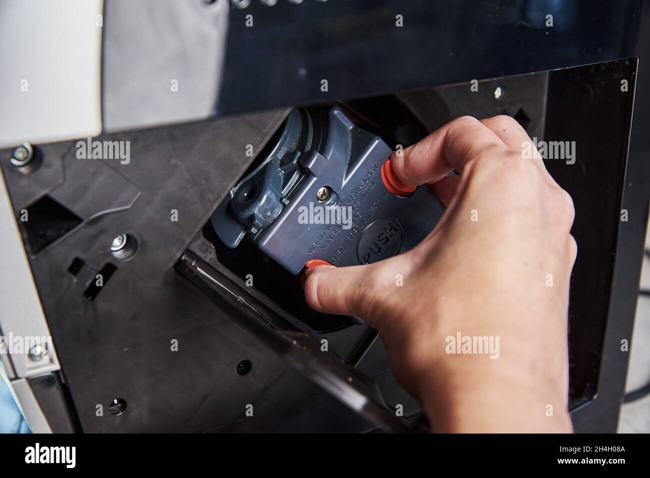 Automatic coffee machine cleaning. Woman inserts mechanism inside coffee machine. Household