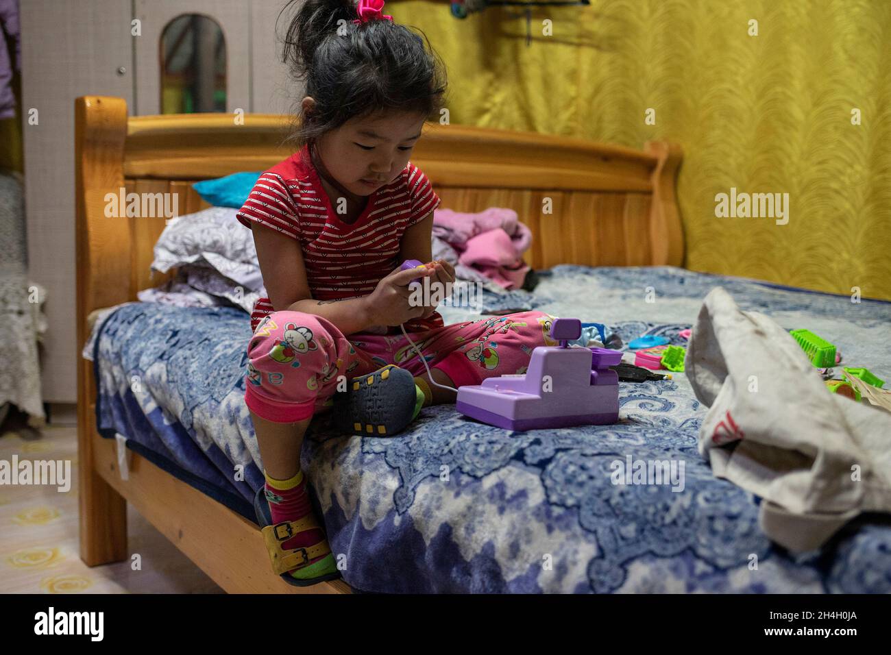 Khngorzul, 4, plays in her home as night approaches in a ger districts of the capital Ulaanbaatar, January 19, 2019. The surrounding hills of Ulaanbaa Stock Photo