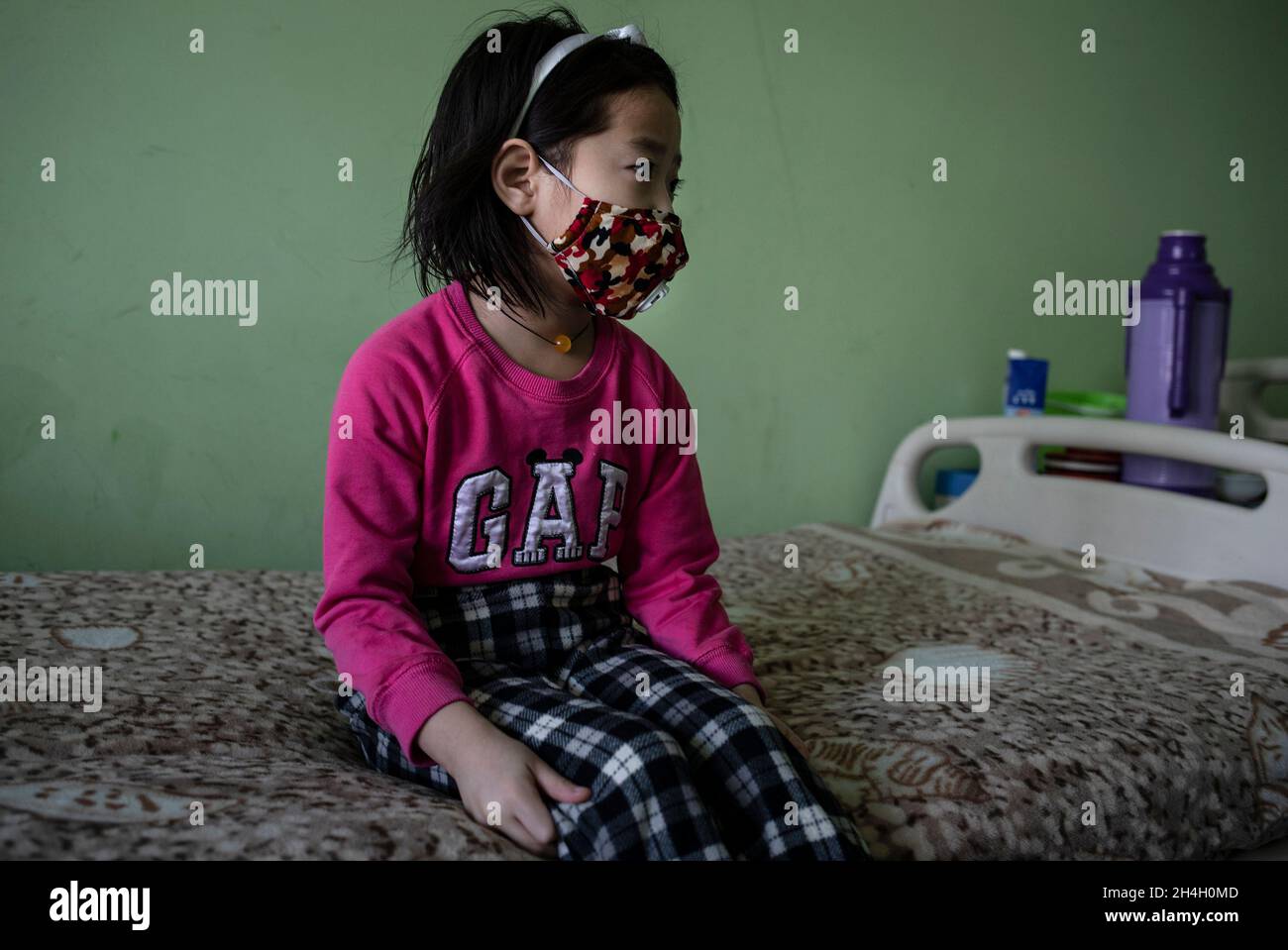 Enkhjin, 6, who suffers from bronchitis sits in a hospital bed in the paediatric in-patient department of a hospital in Ulaanbaatar, January 19, 2019. Stock Photo
