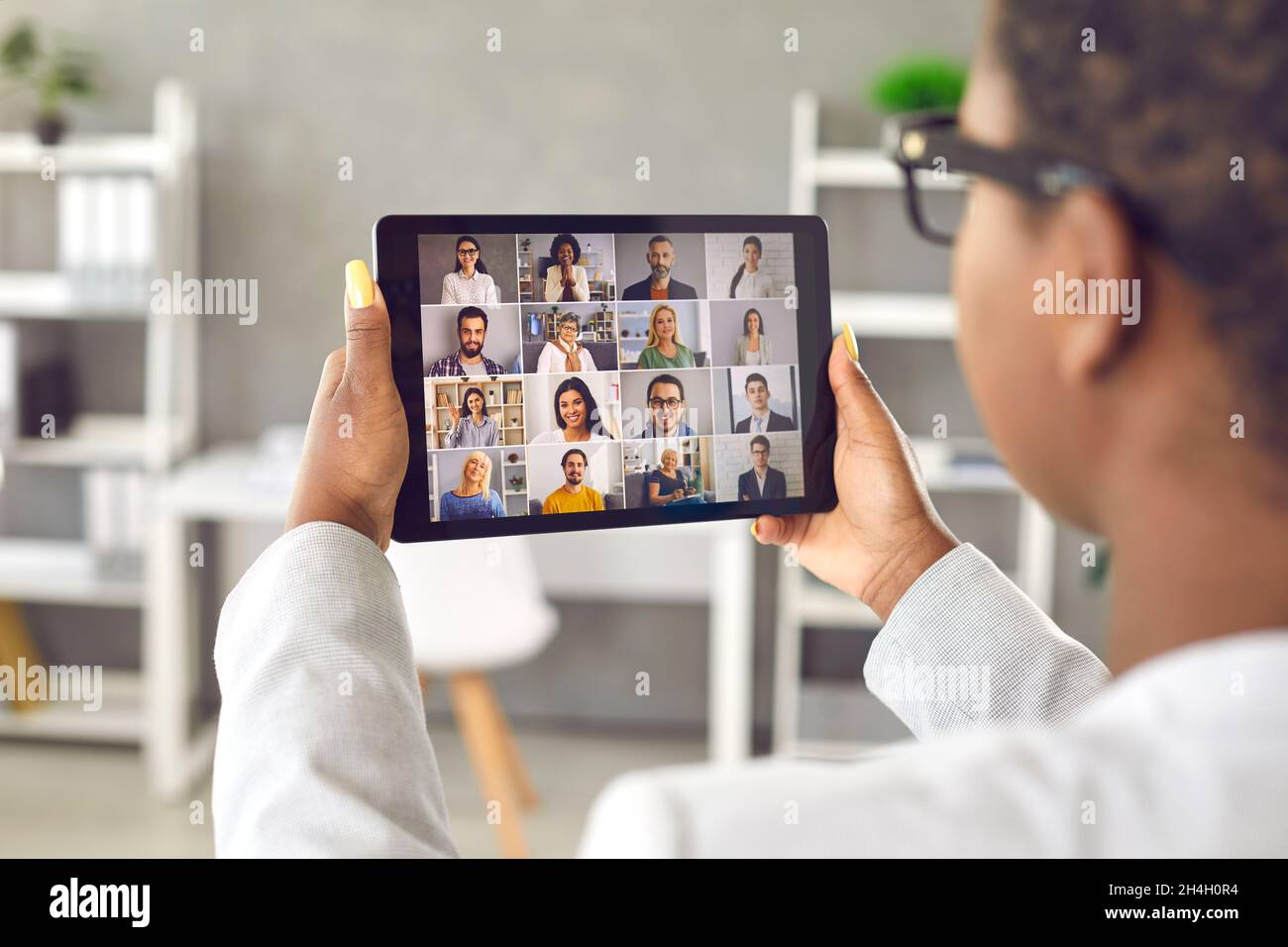 Woman holding tablet and having virtual business meeting with team of diverse people Stock Photo