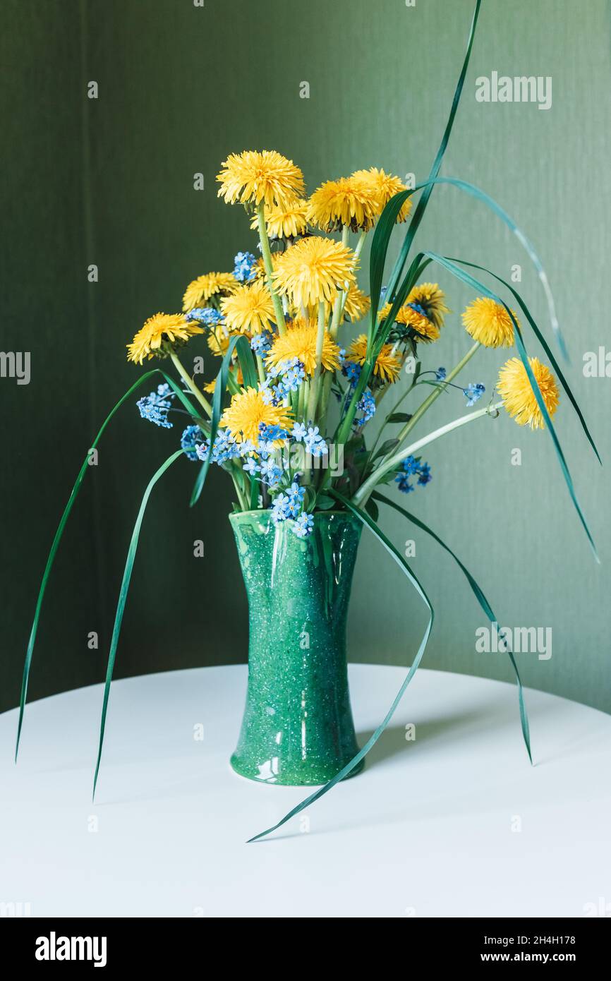 Beautiful bouquet of yellow dandelions in green clay vase standing on ...
