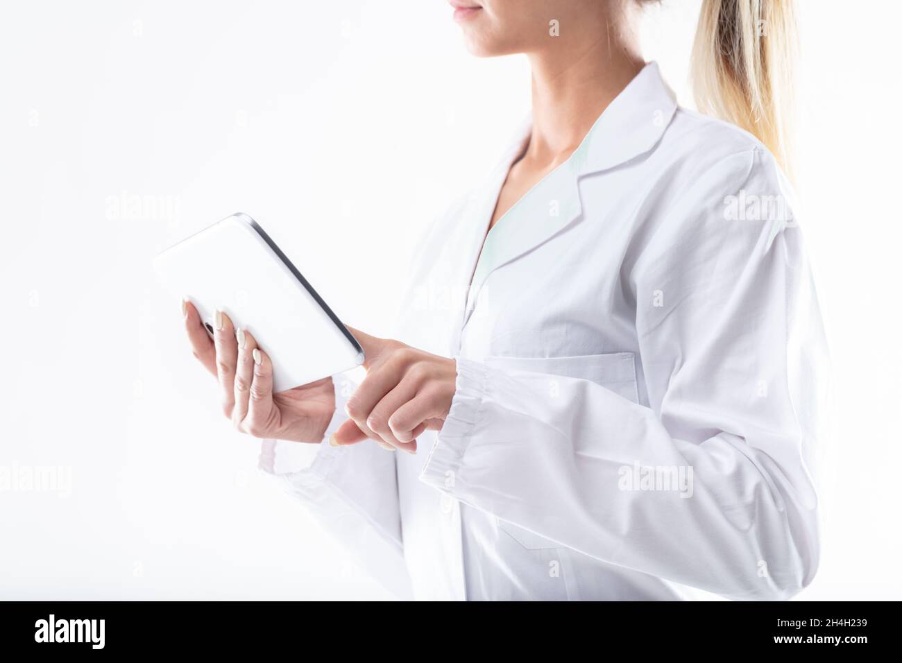 Woman in a white lab coat using a handheld tablet pc in a close up ...