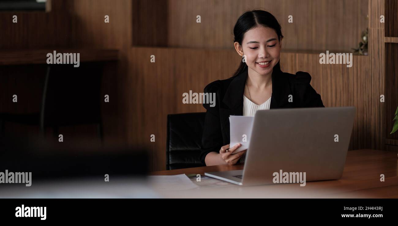 Charming Asian woman working at the office using a laptop. business ...