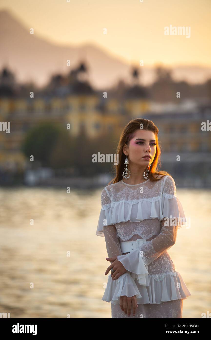 A bride in a white wedding dress in the old town of Austria at sunset. Stock Photo