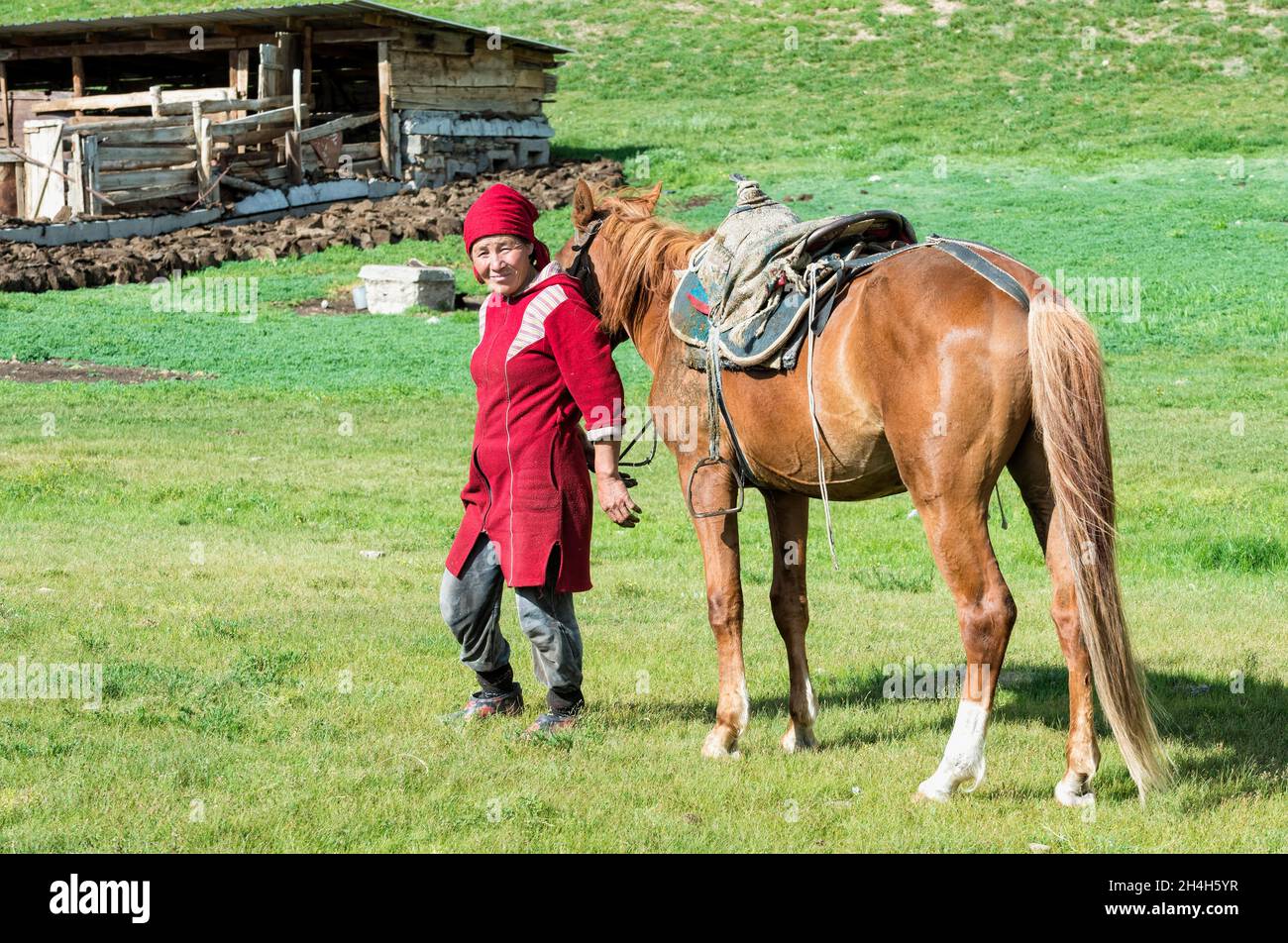 Kyrgyz woman with horse, Sary Jaz valley, Issyk Kul region, Kyrgyzstan Stock Photo