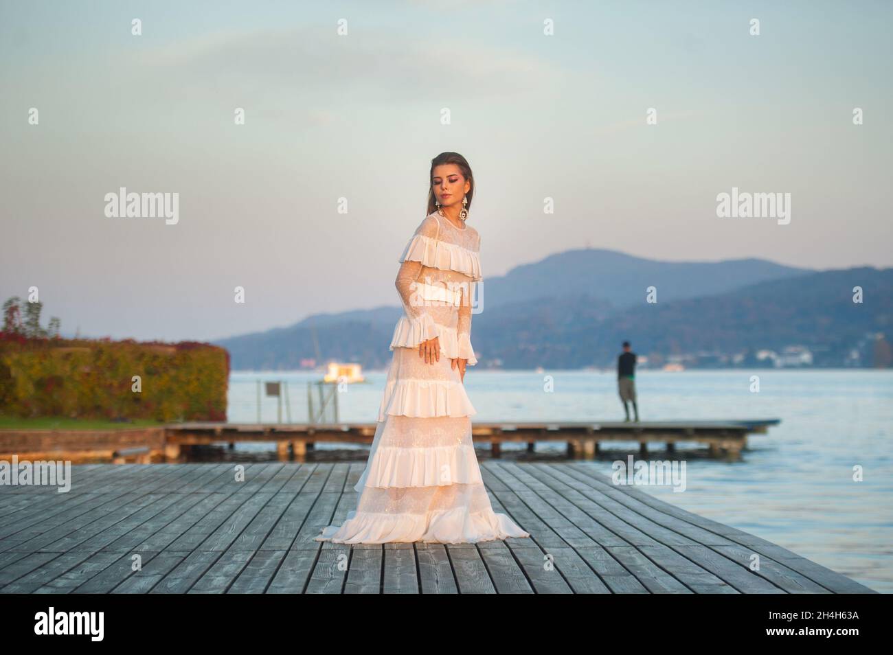 A bride in a white wedding dress in the old town of Austria at sunset. Stock Photo