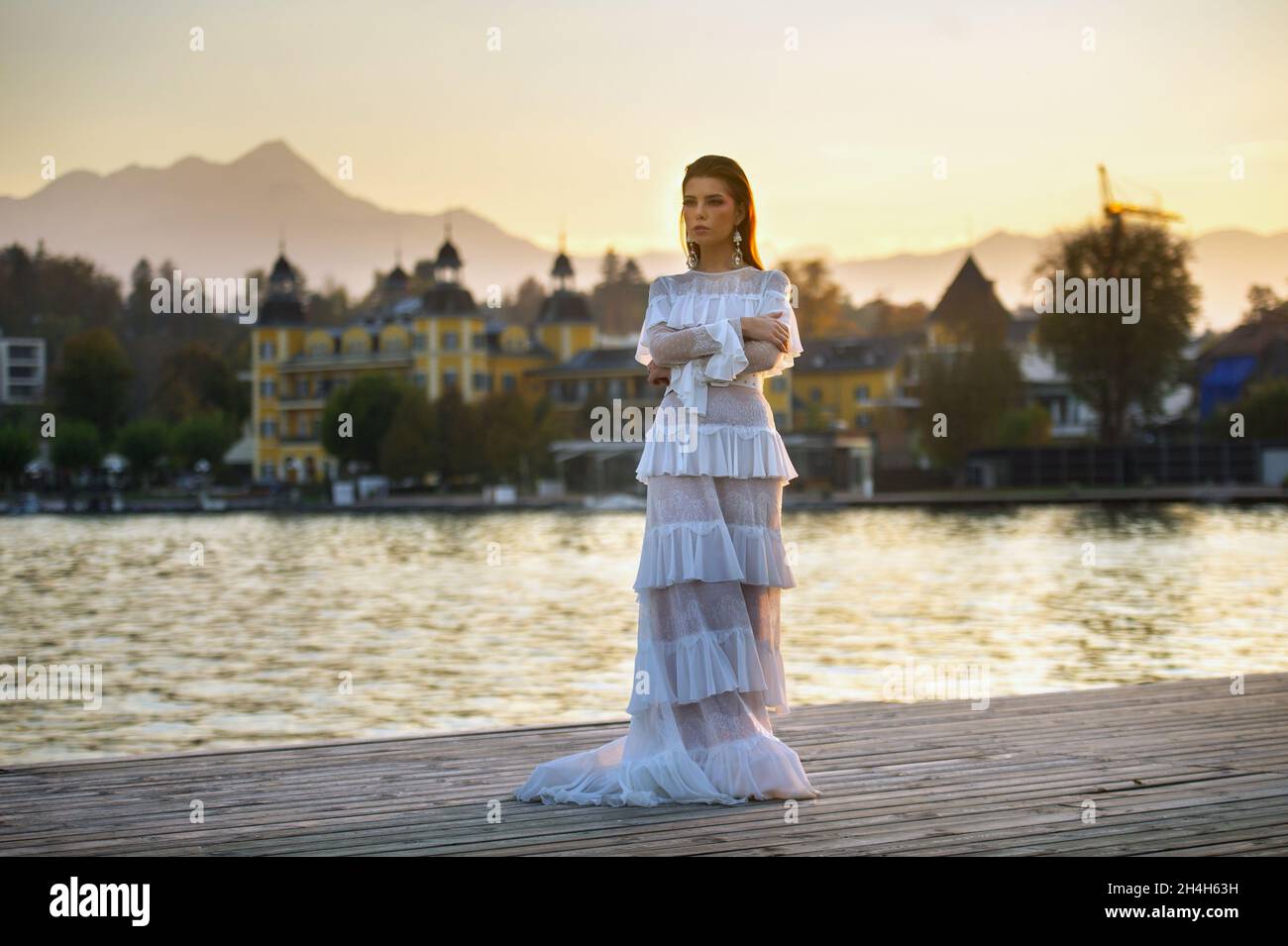 A bride in a white wedding dress in the old town of Austria at sunset. Stock Photo