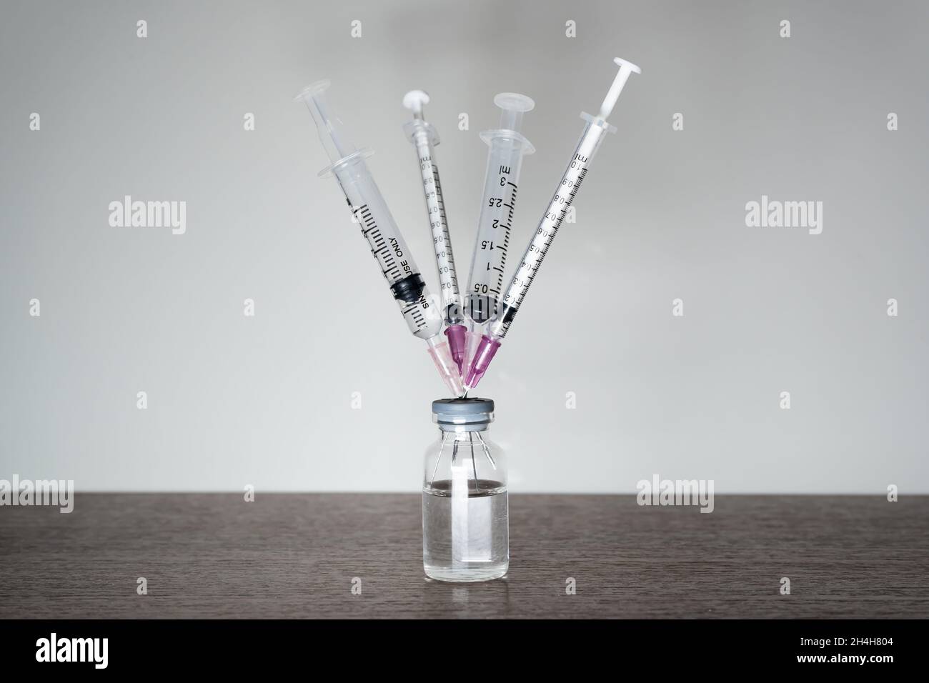 A vaccine vial with 4 syringes. A fourth dose Covid-19 vaccine booster shot concept. Stock Photo
