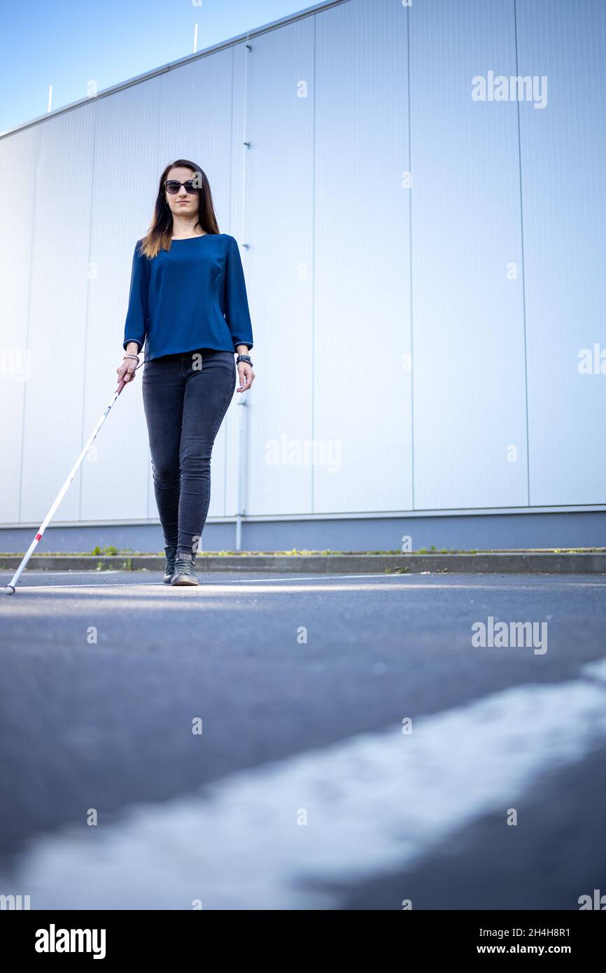 Blind woman walking on city streets, using her white cane to navigate the  urban space better and to get to her destination safely Stock Photo - Alamy