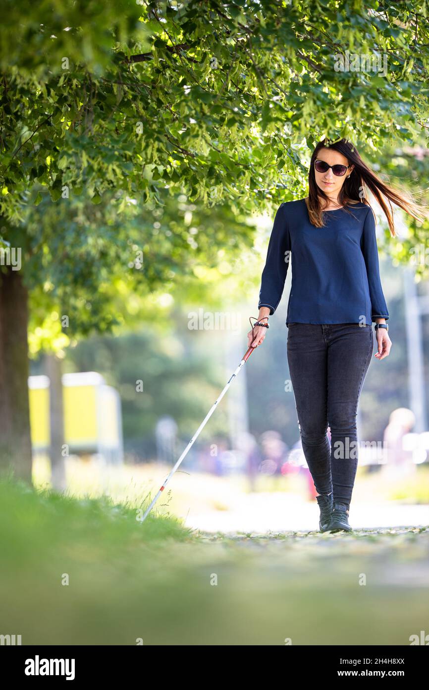 Blind woman walking on city streets, using her white cane to navigate the  urban space better and to get to her destination safely Stock Photo - Alamy