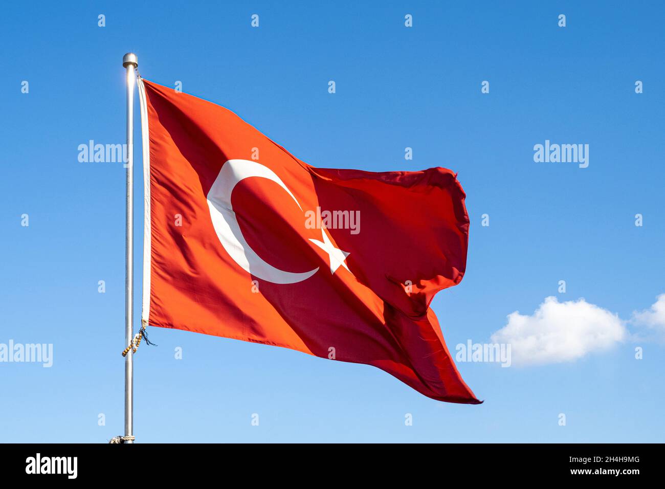 Turkish flag or flag of Turkey waving on flagpole against blue sky in Istanbul. Space for text. Stock Photo