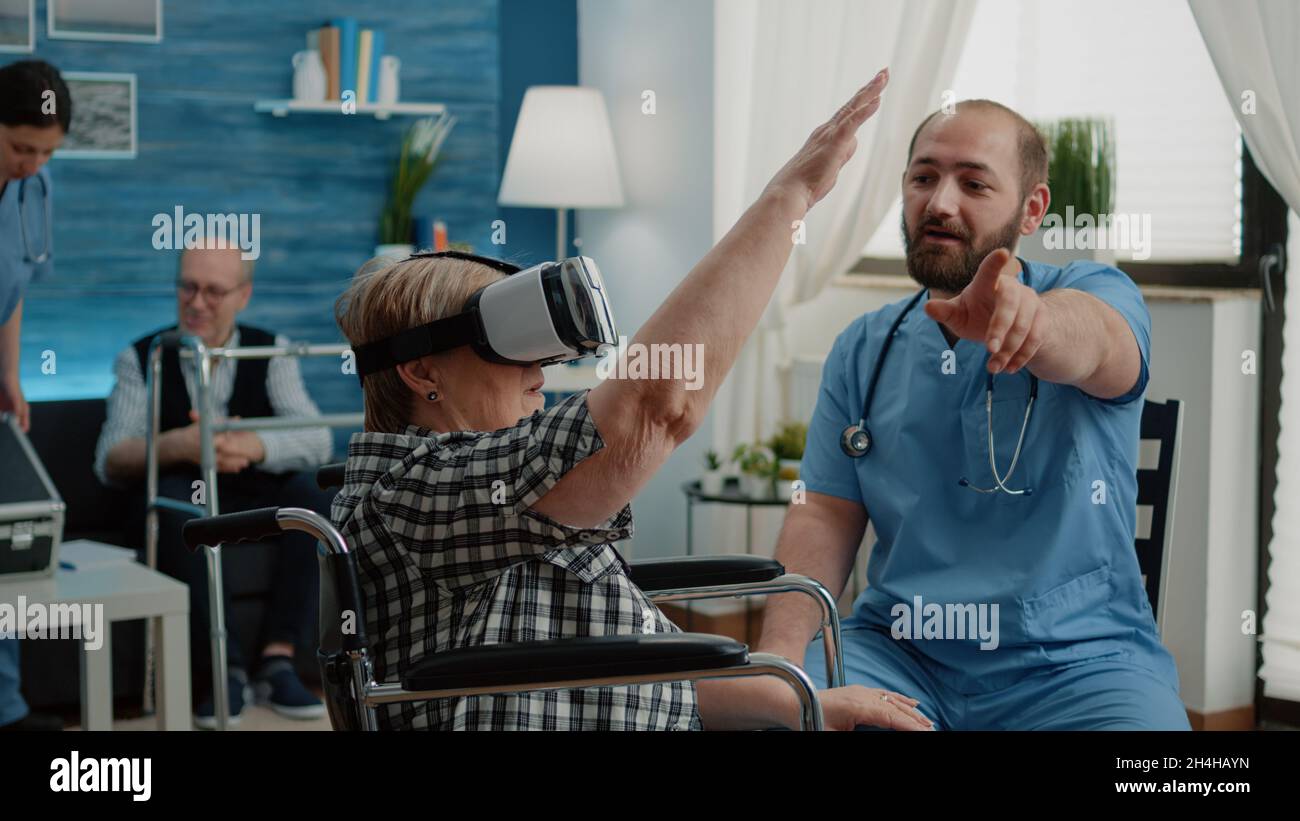 Disabled old woman in wheelchair using vr glasses in nursing home while ...