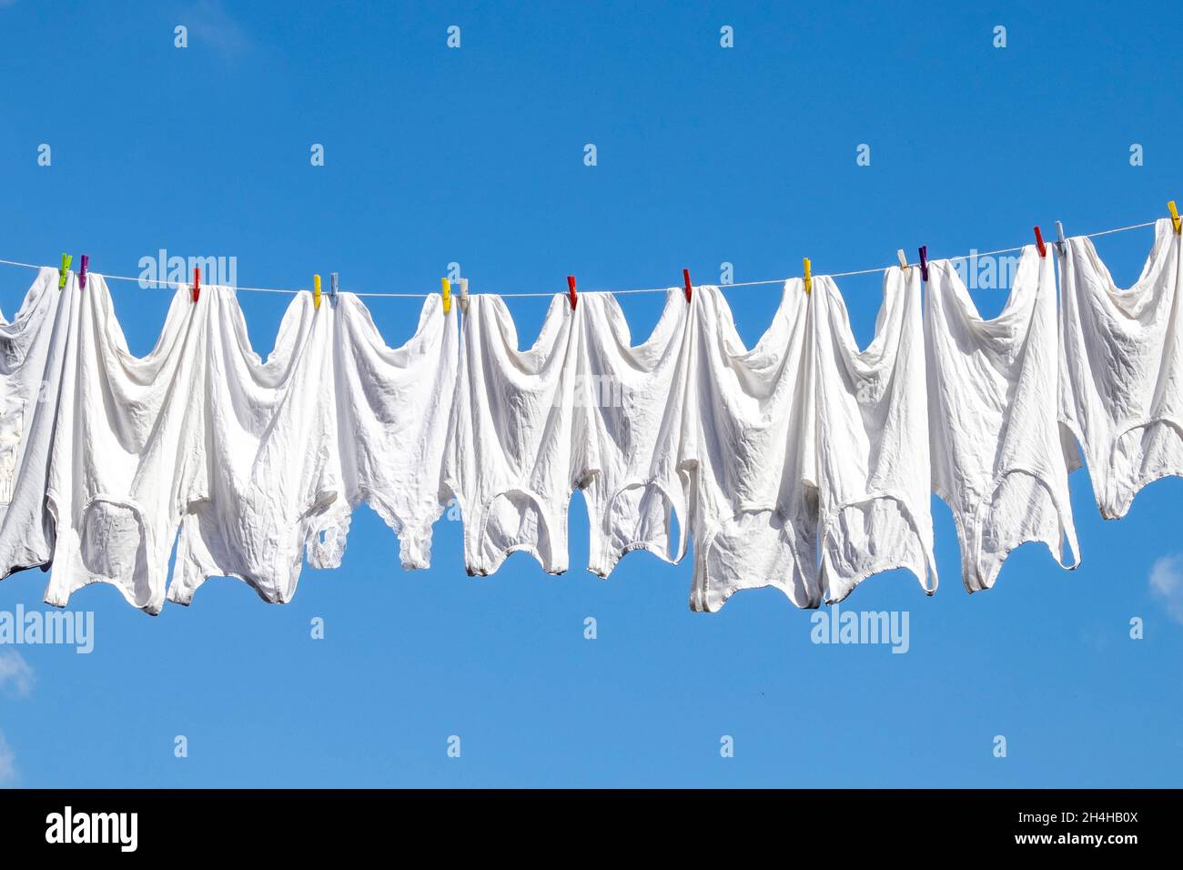 Clothesline, rope with clean white clothes during sunny summer day against blue sky. Clothes